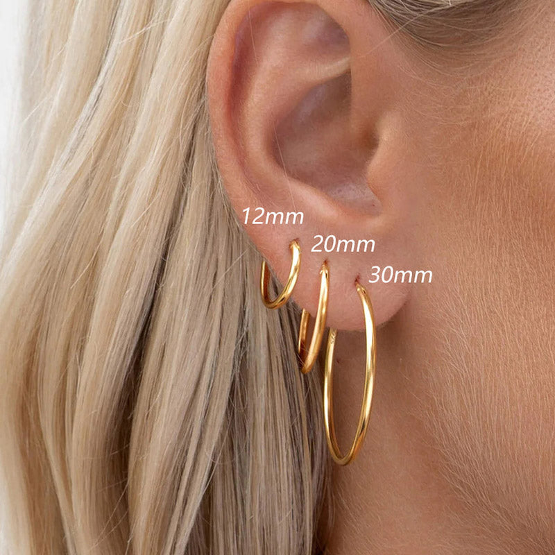 A model wearing the set of three gold hoop earrings to show scale.