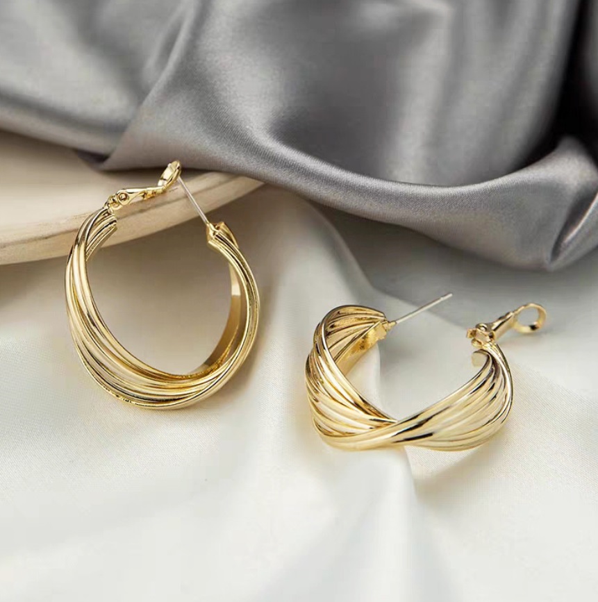 Detailed close-up of the twisted wire design on the criss-cross gold hoop earrings.