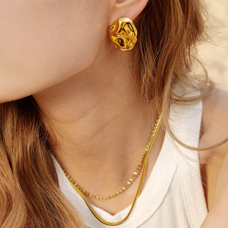 A model showcasing the elegant gold hammered stud earrings with matching necklaces.