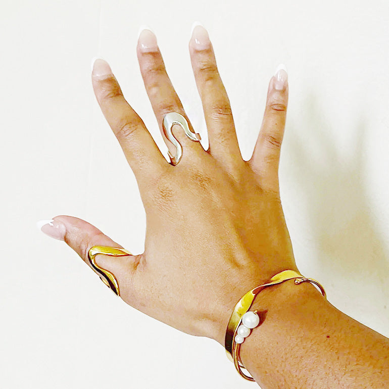 A hand modeling the unique gold geometric rings from the stainless steel set.