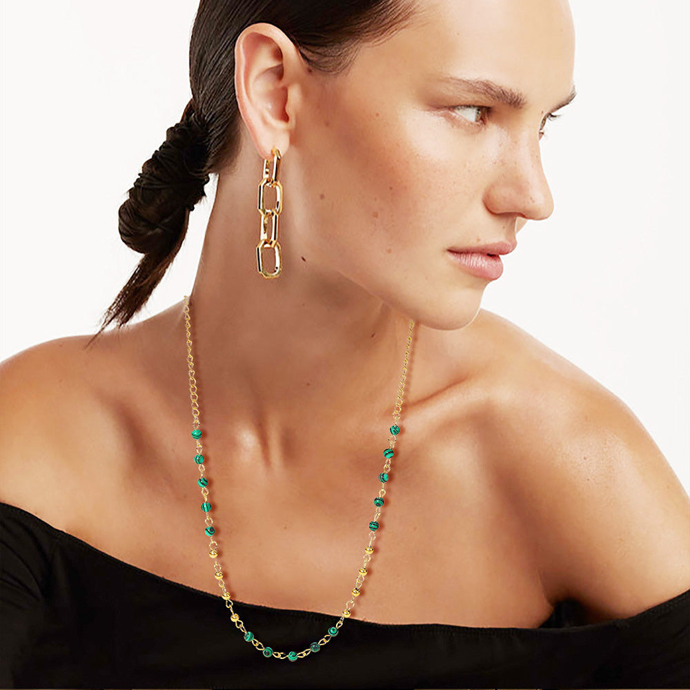 Model showcasing the layered look of the gold and green beaded stainless steel necklaces.