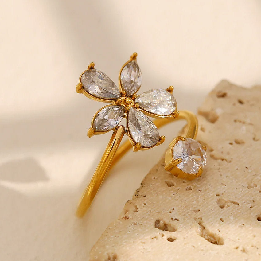A set of gold-plated flower jewelry including a ring and bracelet with clear gemstones
