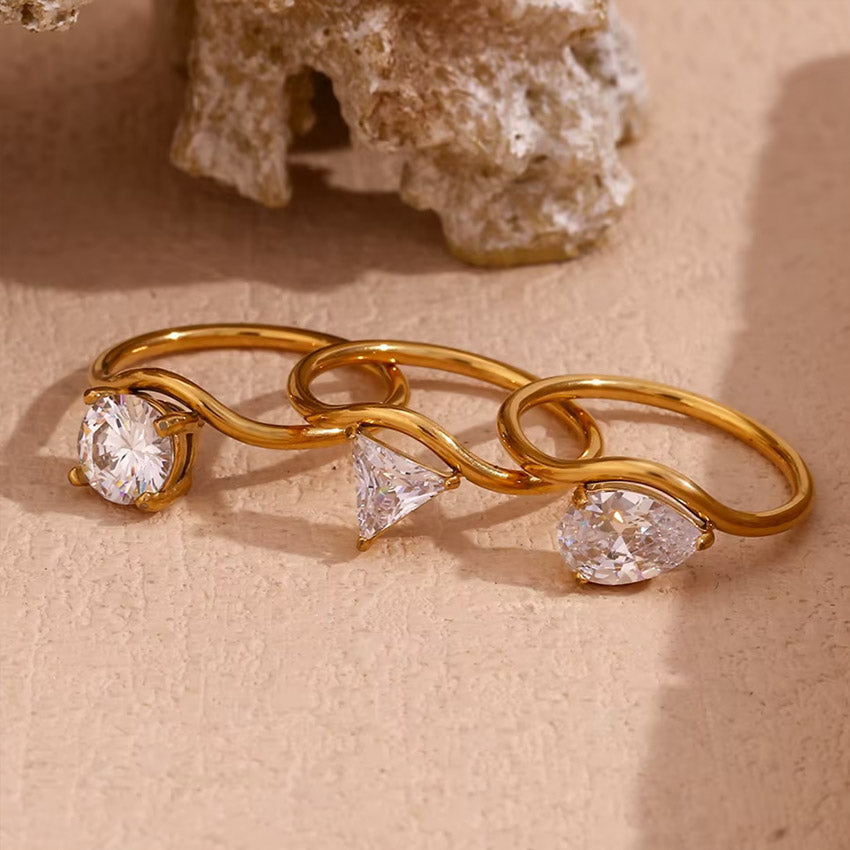 A close-up product shot of the geometric wavy zircon solitaire rings in three different stone shapes.