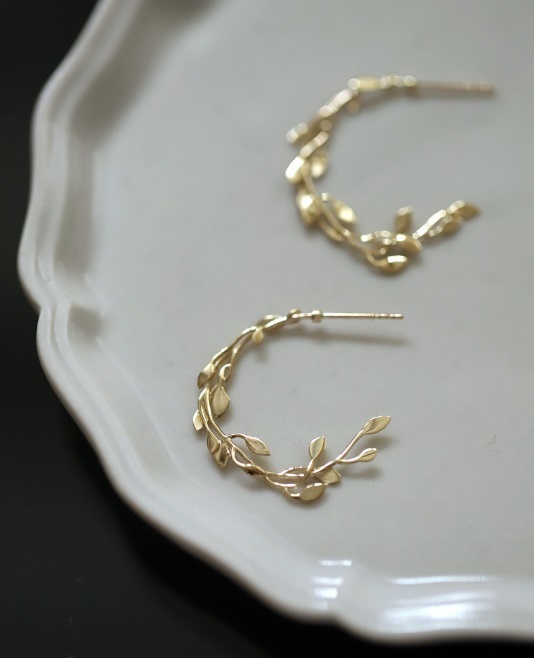 Close-up of the leafy design on the gold-plated hoop earring