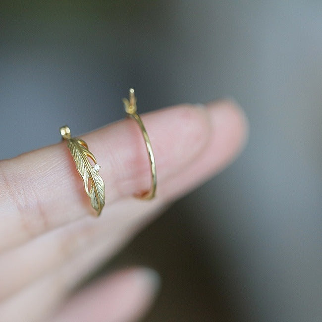 Detailed close-up of the feather and leaf design on the 14K gold plated hoop earrings