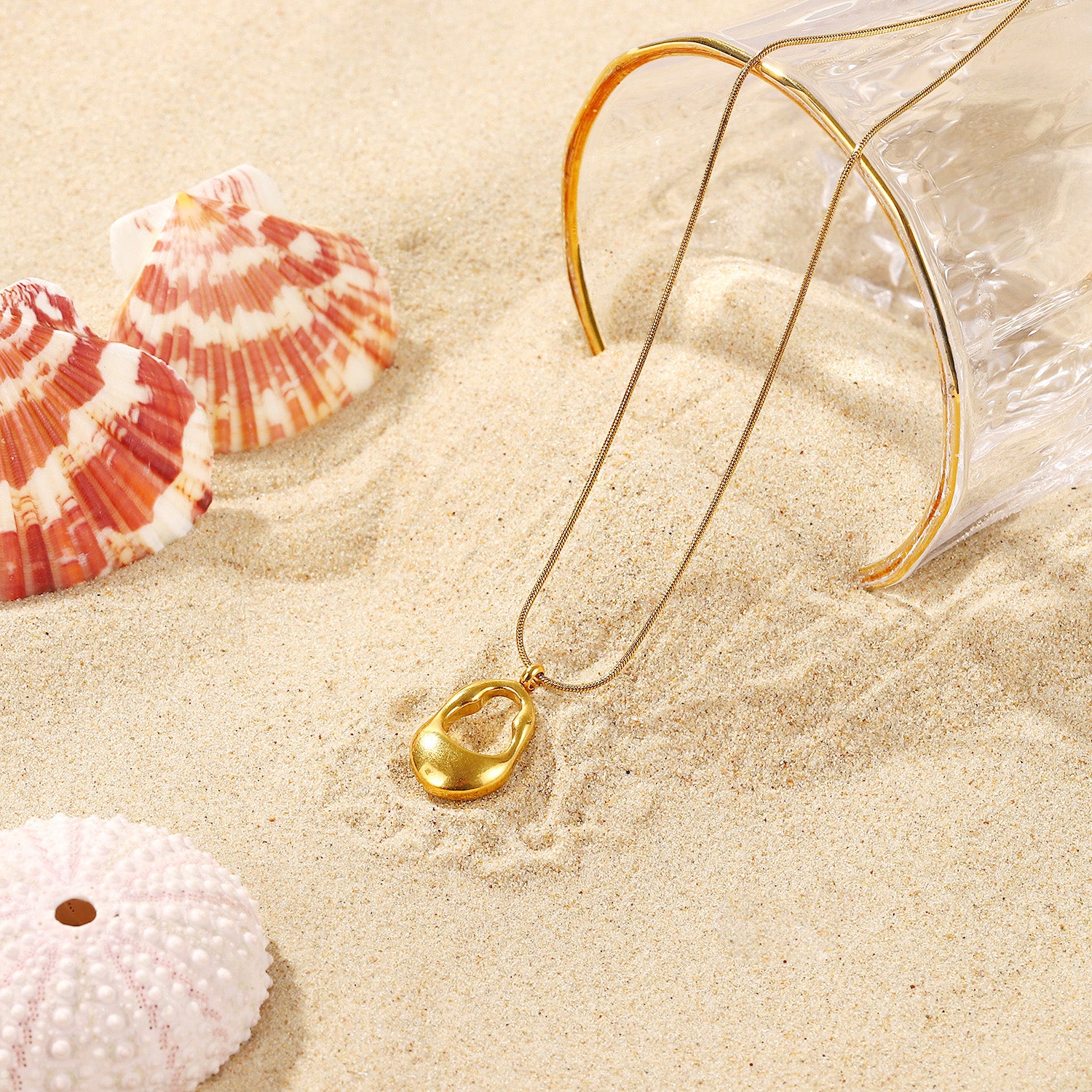 A stylish shot of the gold-tone oval pendant necklace in a beach-themed setting with seashells.