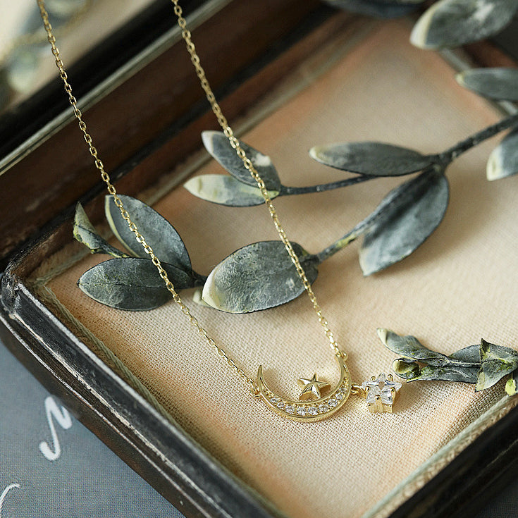 Gold star and moon pendant necklace presented in a decorative box