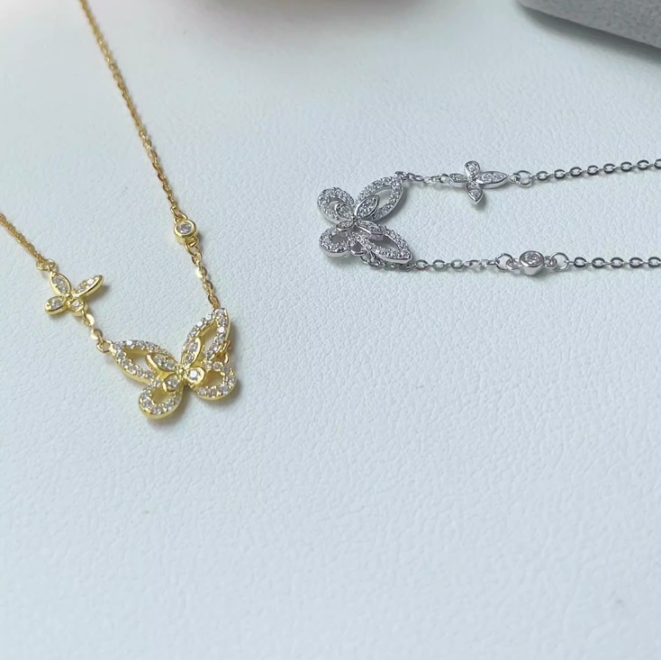 A gold version of the butterfly necklace alongside a matching silver bracelet, highlighting the available customization options.
