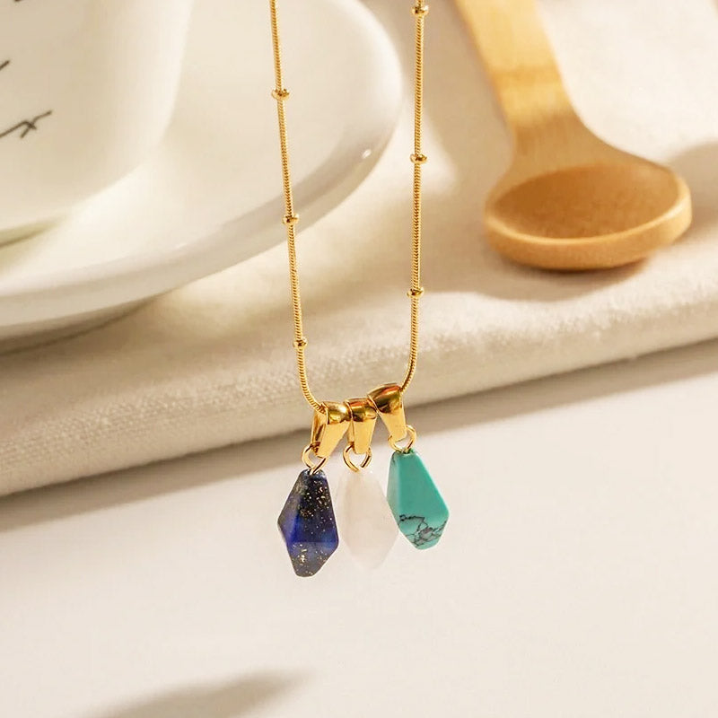 A gold necklace showcasing three of the natural stone pendants