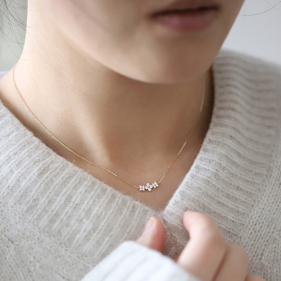 A woman models the elegant three-flower zircon pendant necklace, highlighting its style and length.