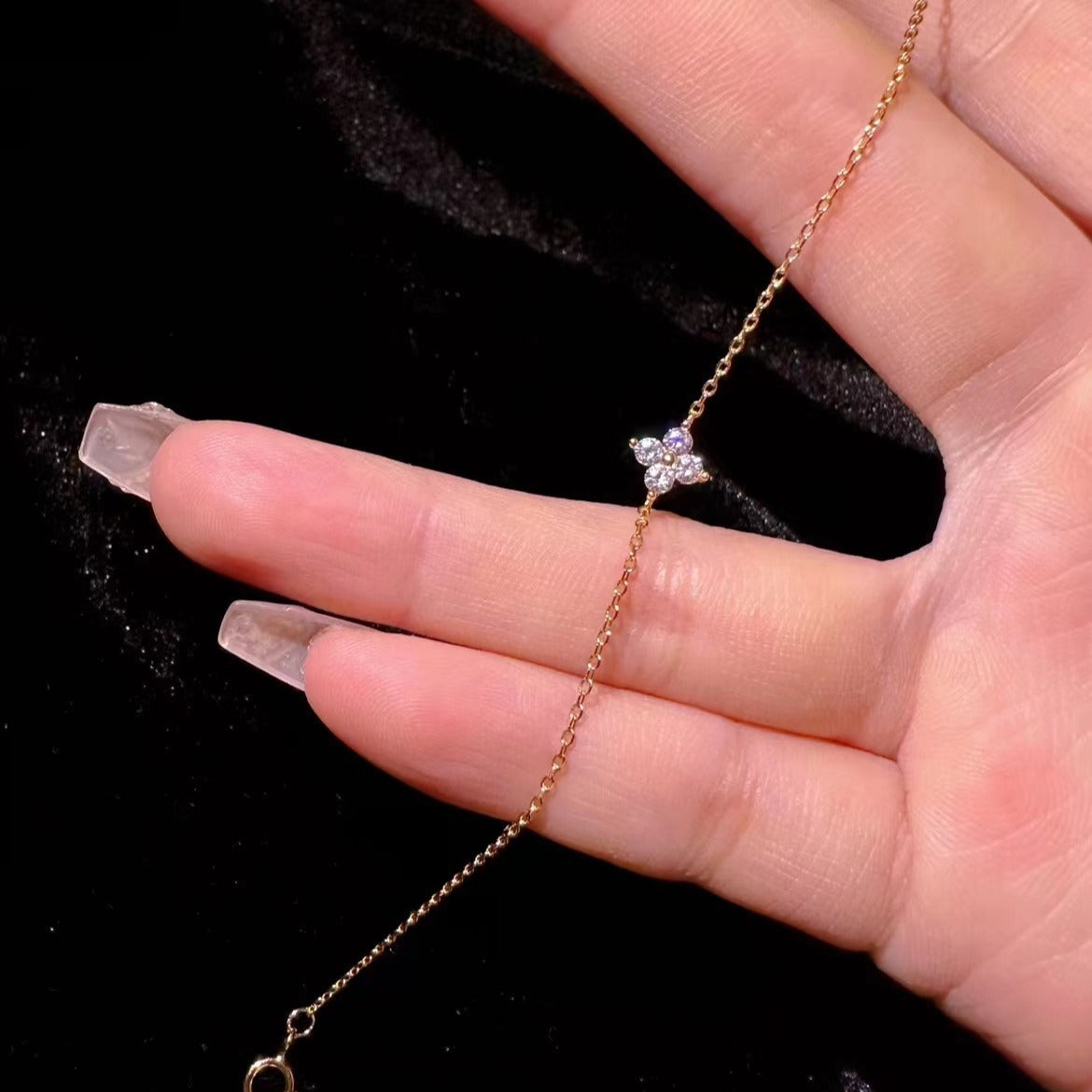 A detailed close-up of the gold-plated four-leaf clover charm with sparkling CZ crystals.