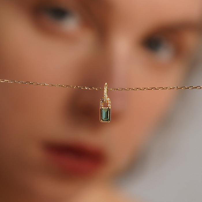 Detailed close-up of the green zircon tiny lock pendant on the 925 sterling silver necklace.