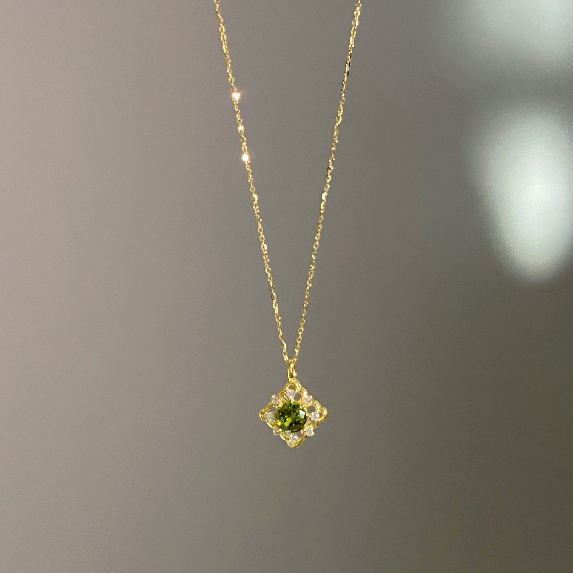 Close-up view of the green zircon pendant on the 14K gold plated sterling silver necklace.