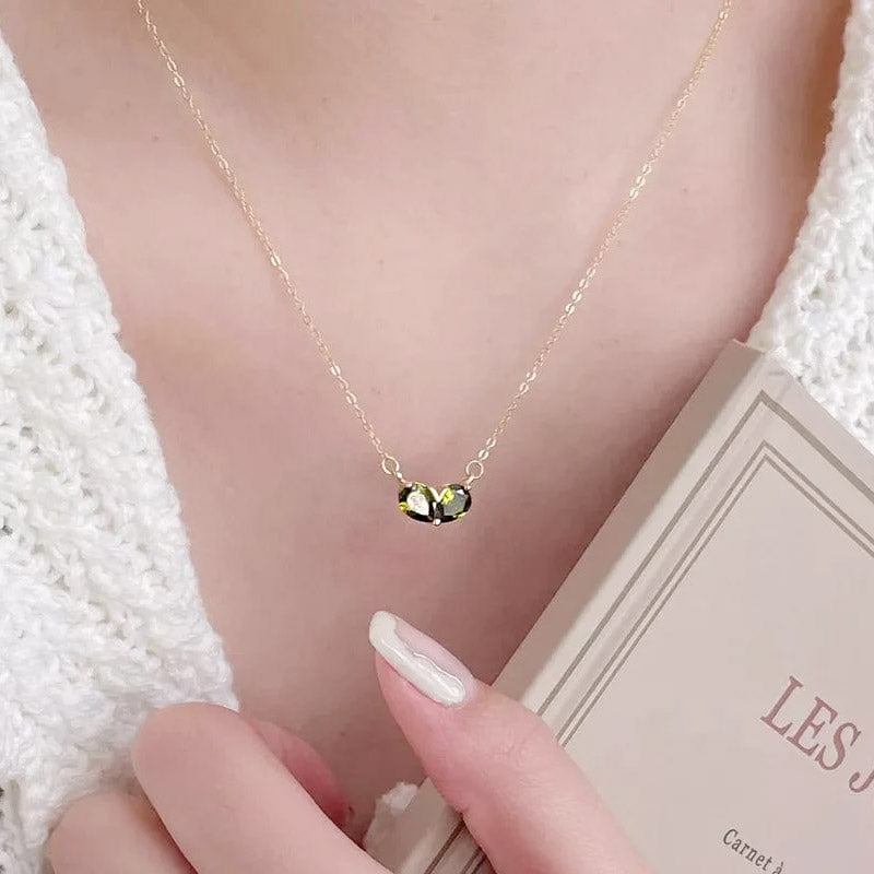 A stylish gold-plated necklace with a vibrant green gemstone pendant