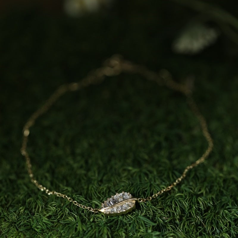 A stunning gold-plated leaf bracelet from the set, displayed on a natural green background