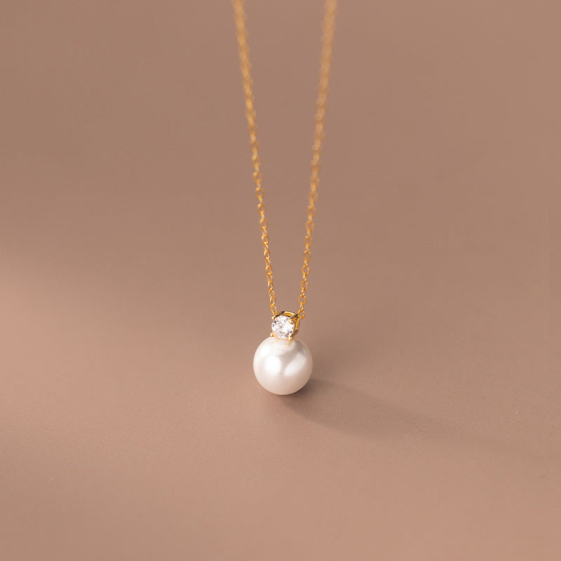 Detailed view of the gold pearl necklace with a sparkling cubic zirconia accent.