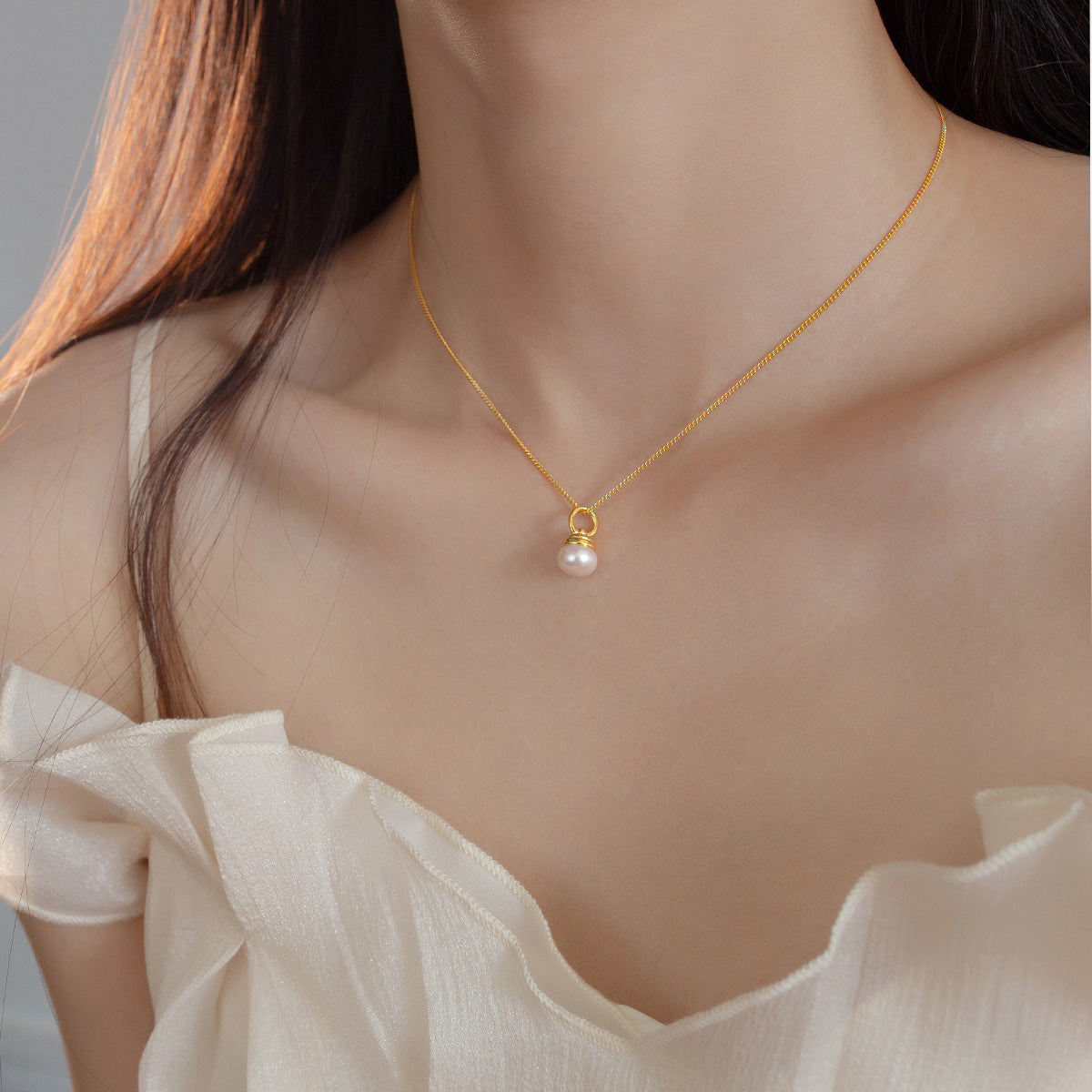 Model showcasing the elegant drape of the gold single pearl necklace.