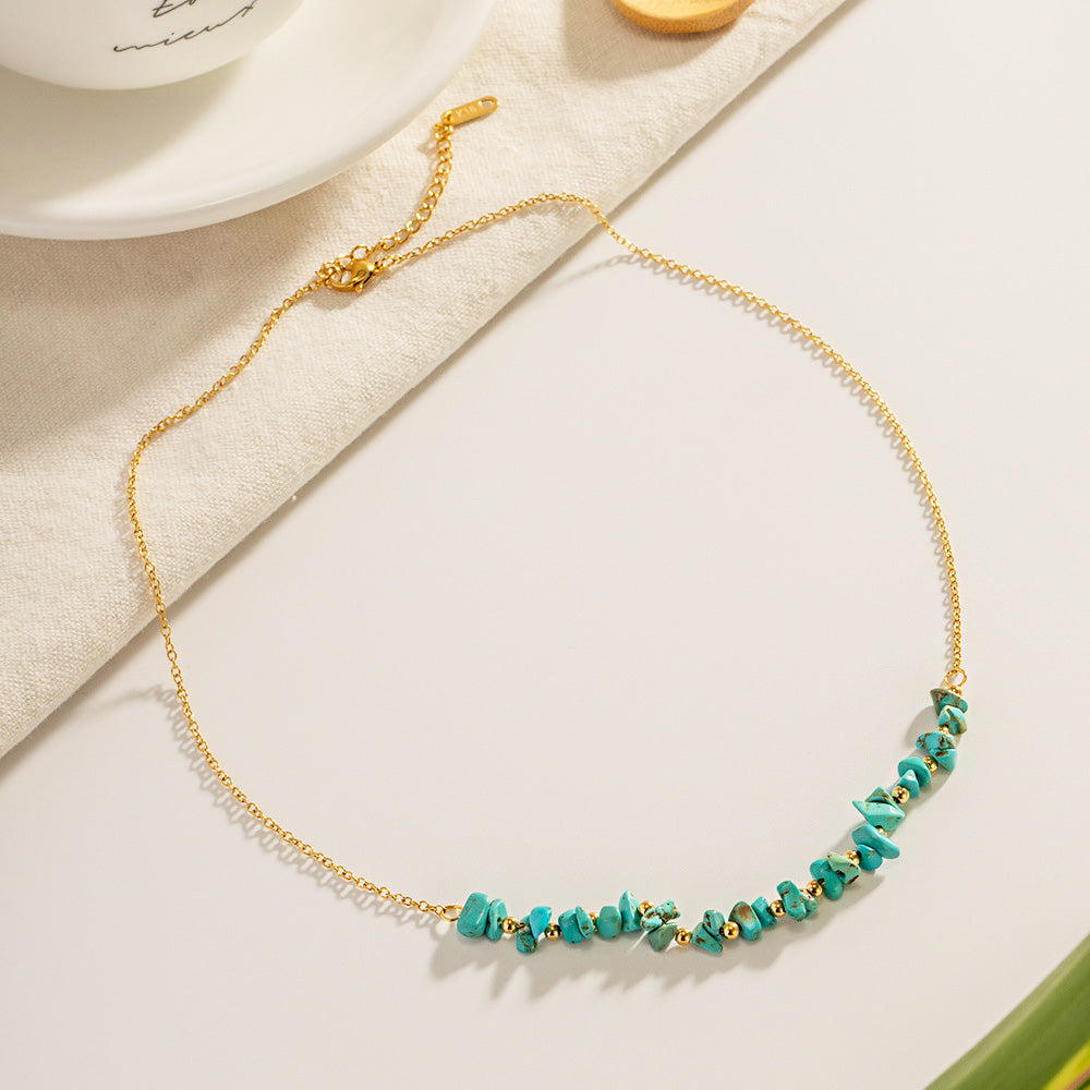 Detailed product shot of the gold-tone necklace with vibrant turquoise stones against a neutral background.