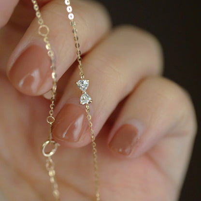 A hand holding the delicate S925 gold bowknot cable chain bracelet