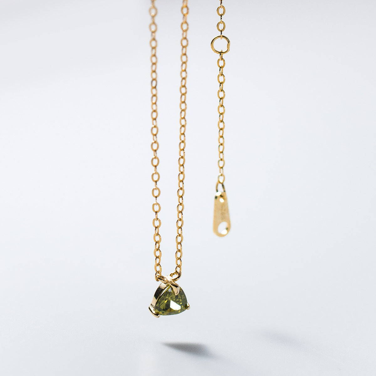 Model showcasing the layered look of the green cubic zirconia triangle necklace set.