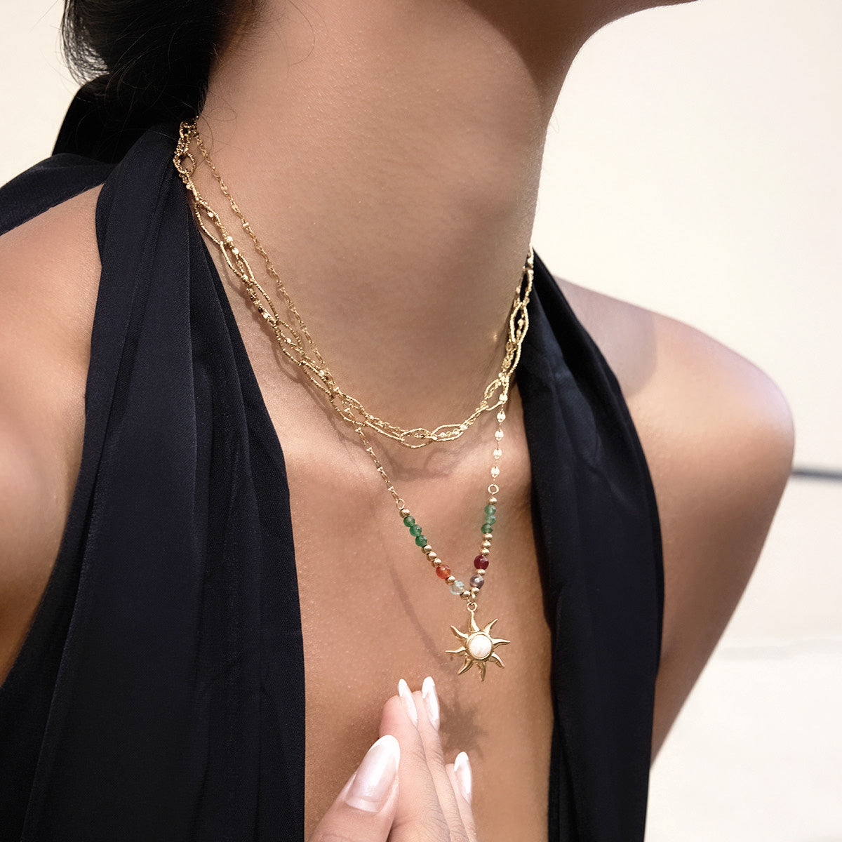 A detailed close-up of the stainless steel sun pendant necklace with colorful beads.