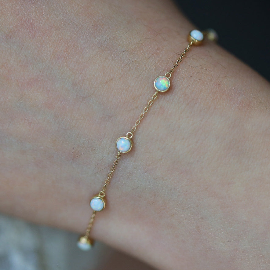 Close-up view of the gold opal bracelet's delicate chain and stones
