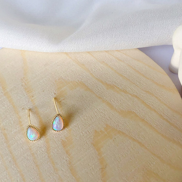 A model showcasing the gold opal teardrop earrings