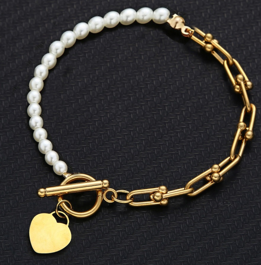 A close-up of the gold-plated Hearty Pearl Toggle Bracelet highlighting its toggle clasp and heart charm.