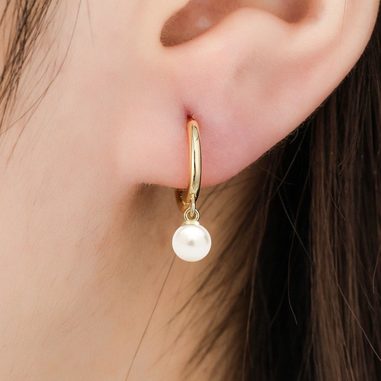 Close-up of the pearl huggie hoop earring on a model