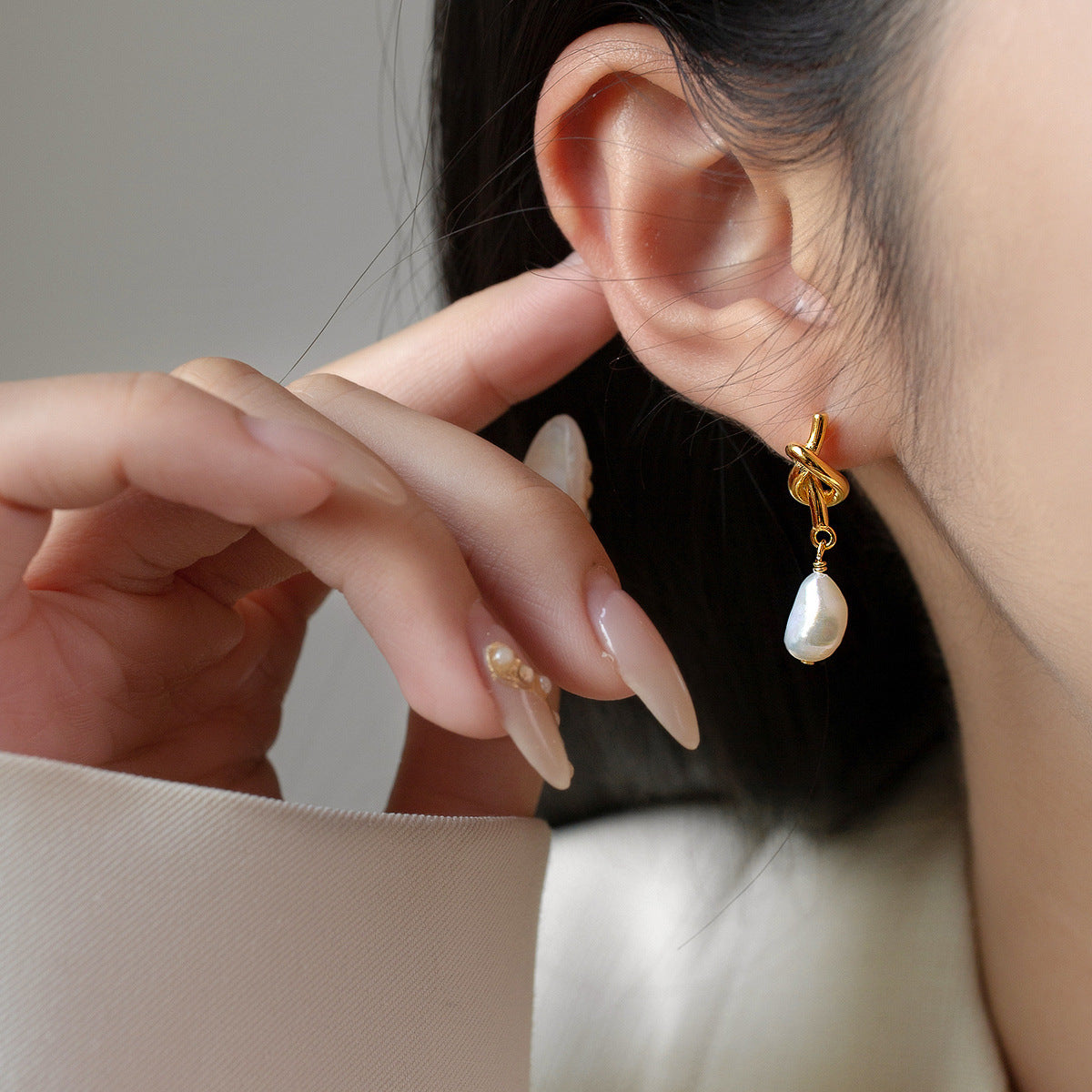 Detailed view of the 18k gold plated knot and pearl drop