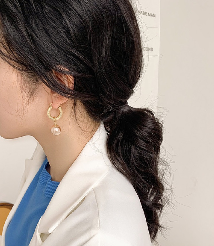 A model wearing the Pearl Vintage Gold Huggie Earrings to showcase their elegant look.