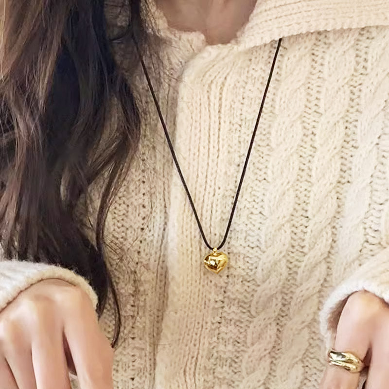 A model wearing the gold heart pendant necklace on a cream sweater