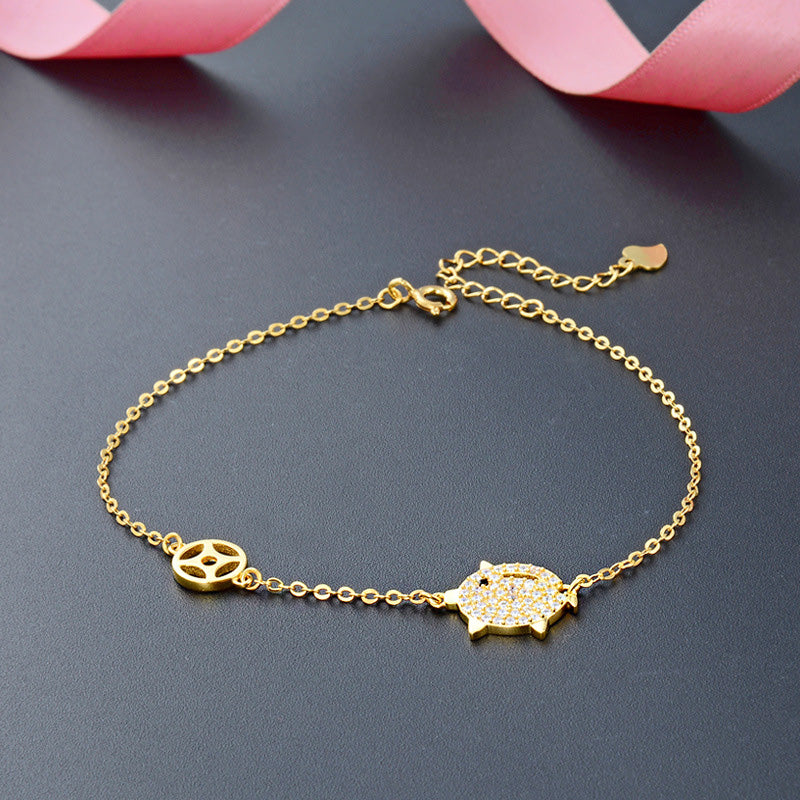A detailed view of the gold-plated pig charm bracelet with pave zircon stones.