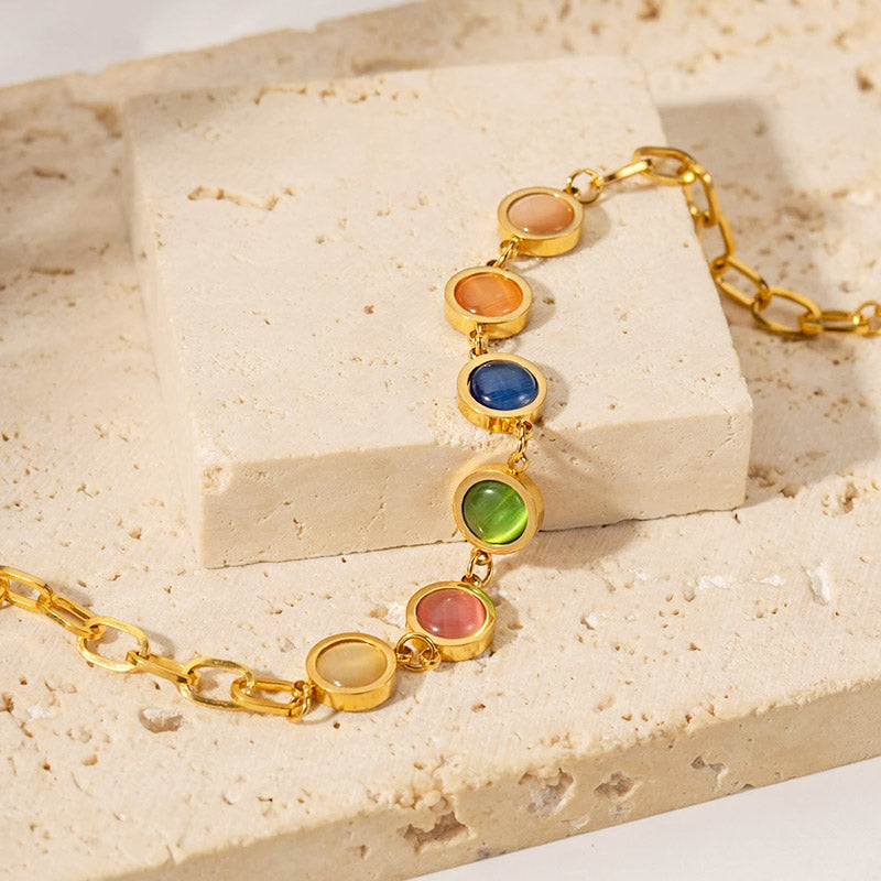 A delicate gold chain bracelet lined with a rainbow of colorful stones.