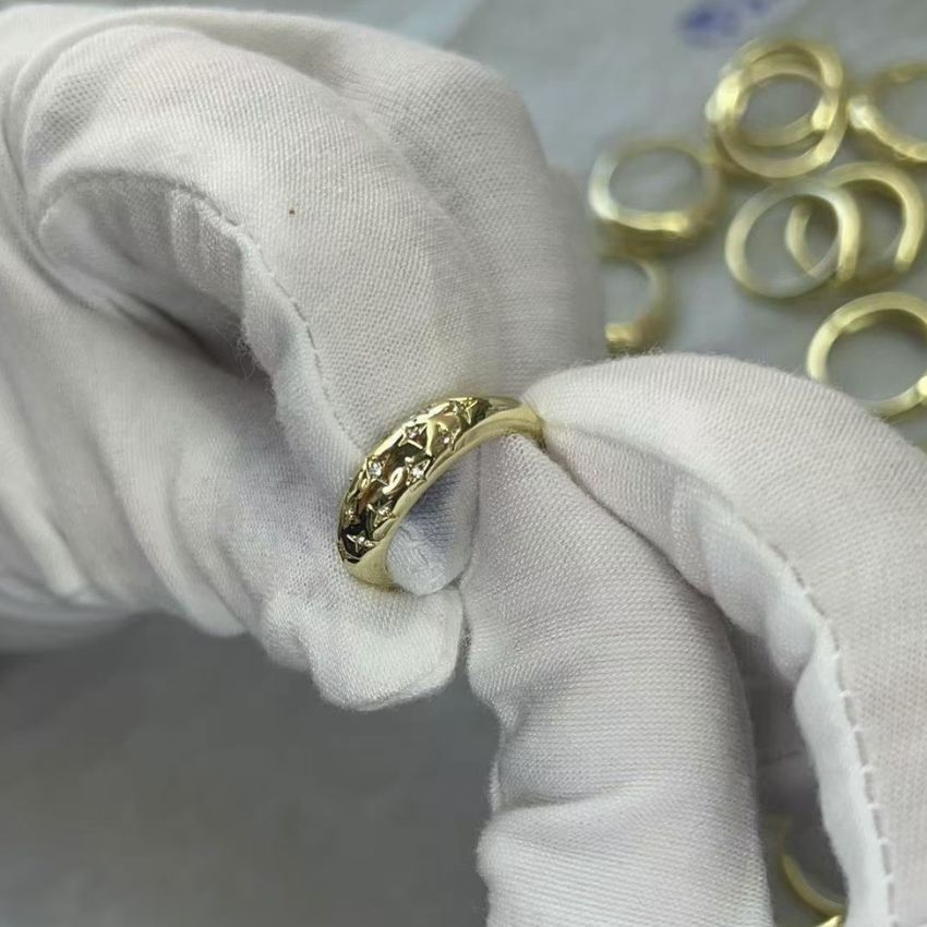 A detailed inspection of a gold ring's textured surface at JR Fashion Accessories.