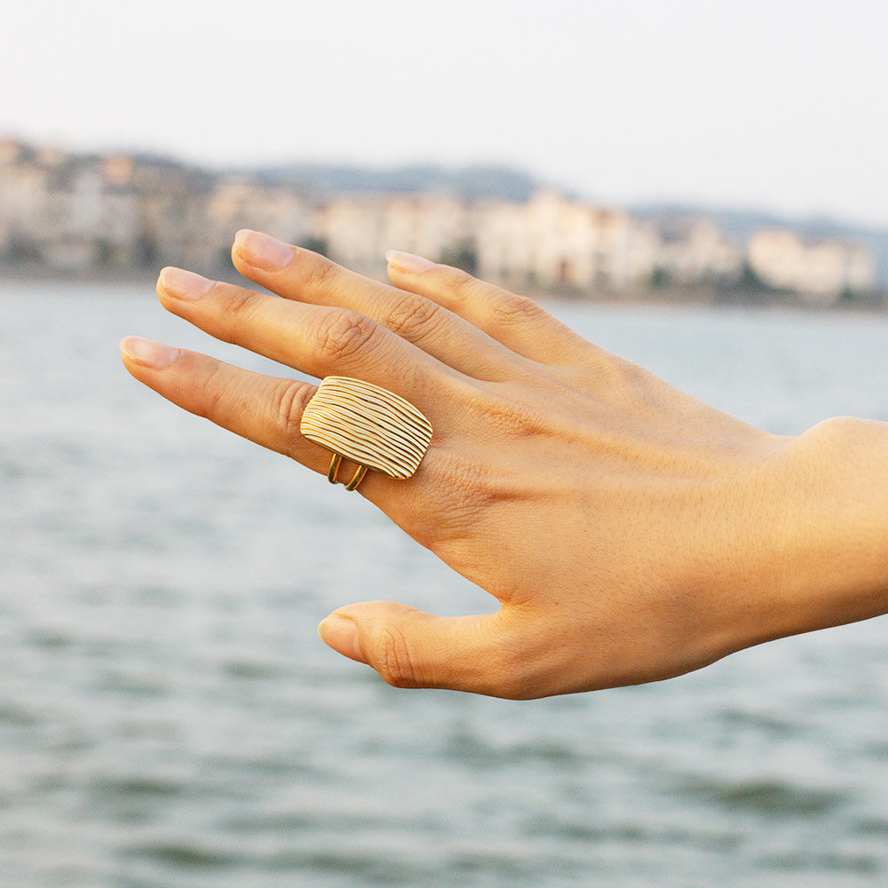 A chunky gold open ring with a distinct horizontal line pattern.