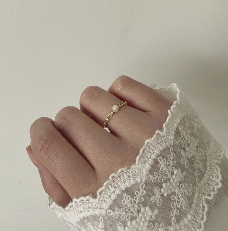 A close-up of the gold 925 sterling silver adjustable pearl ring worn on a finger.