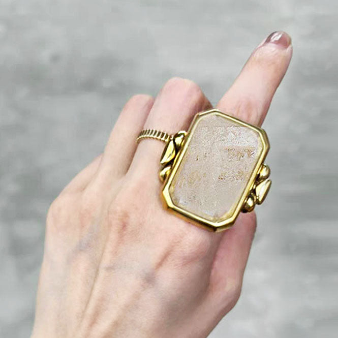 A close-up of a gold vintage ring with a large rectangular transparent stone
