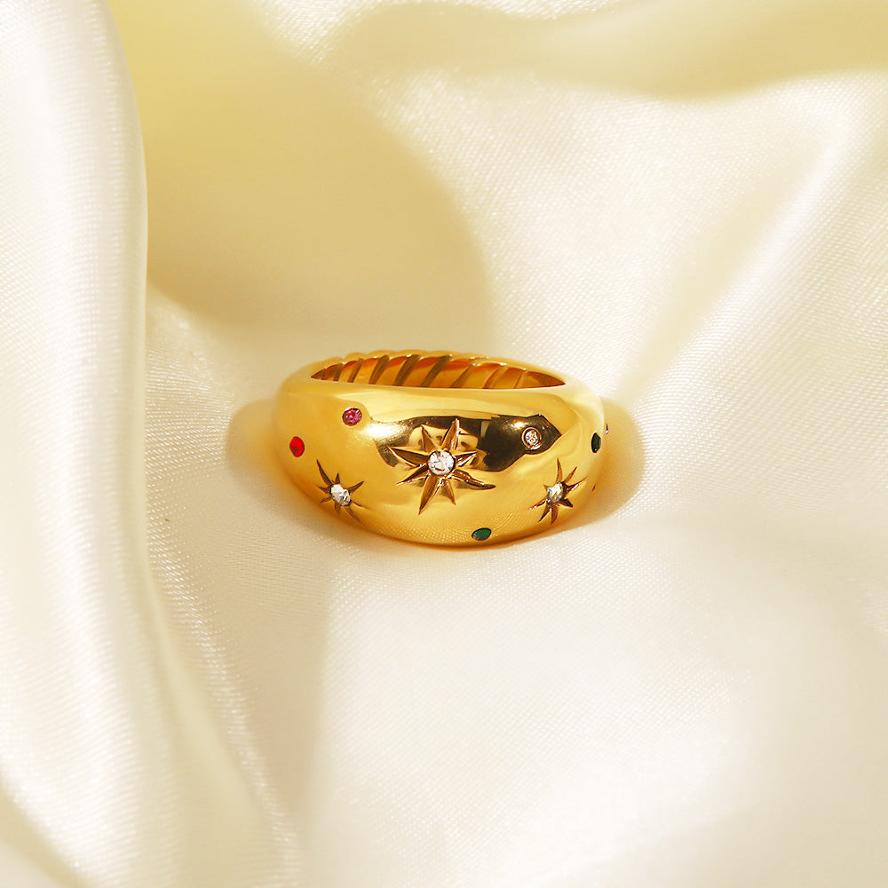 Detailed view of the gold star ring with multi-colored stones on a satin background
