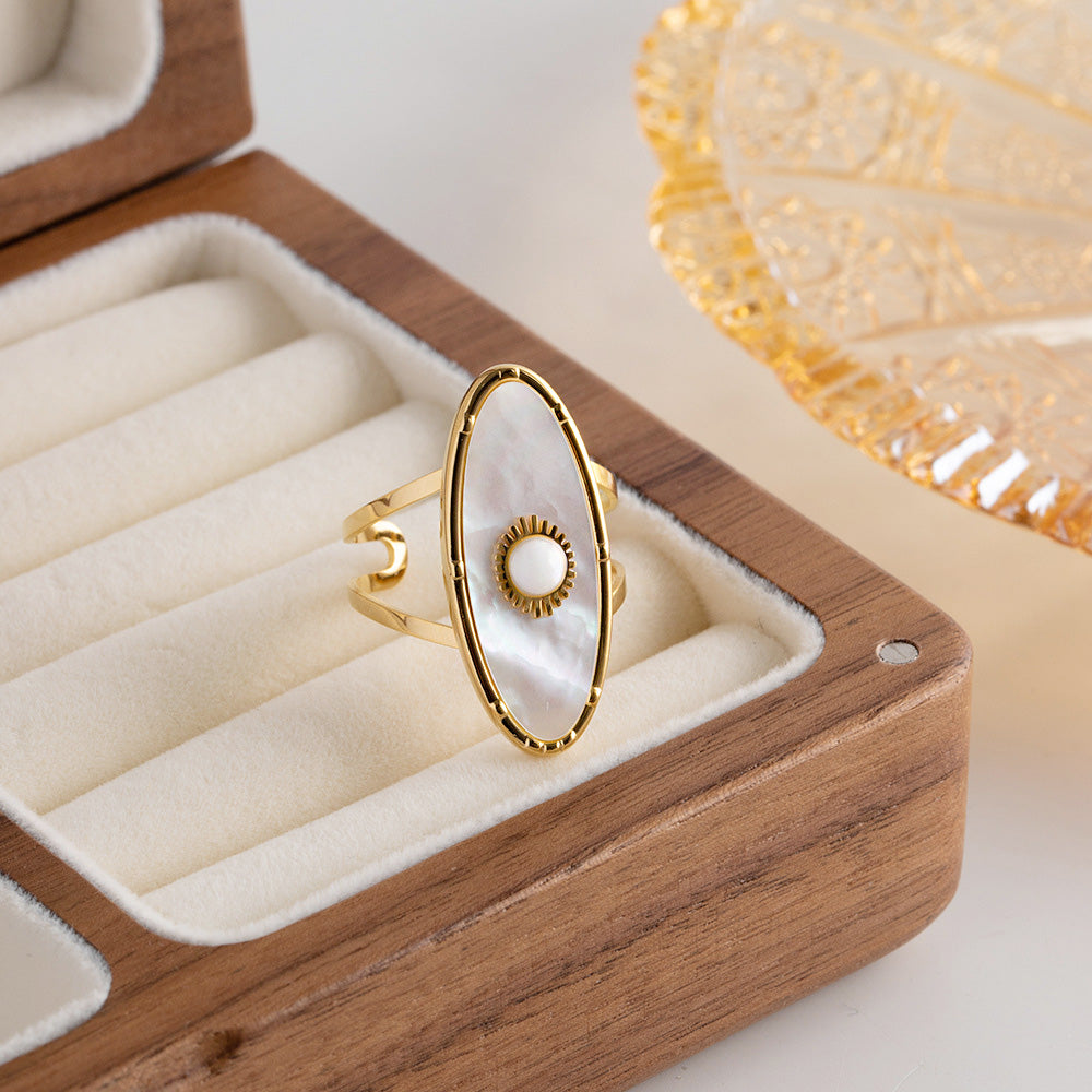 A gold ring with a distinctive white stone design from the set, presented in a luxurious wooden box.