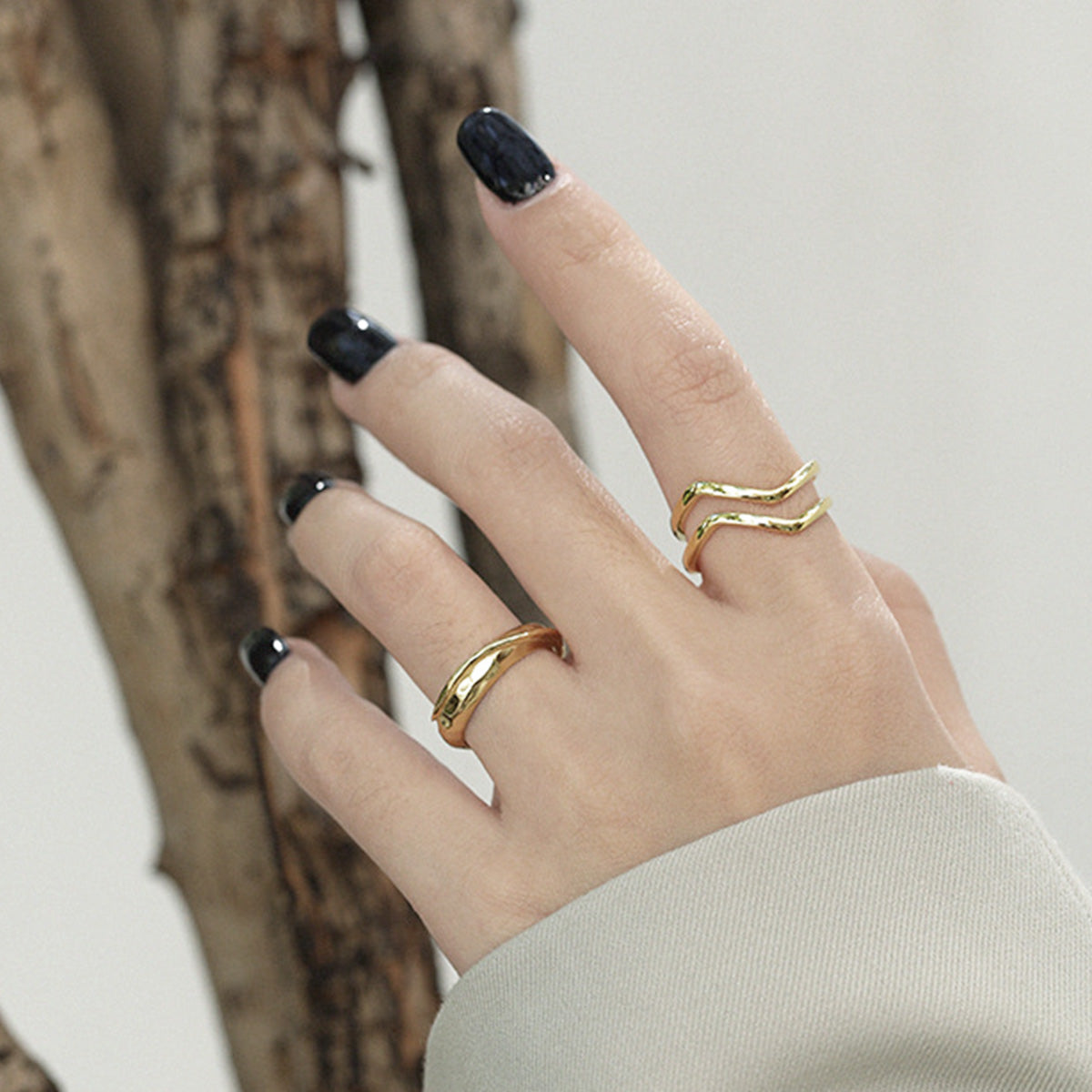 A woman's hand elegantly wearing the 18K gold-plated wave ring to showcase its fit and style.