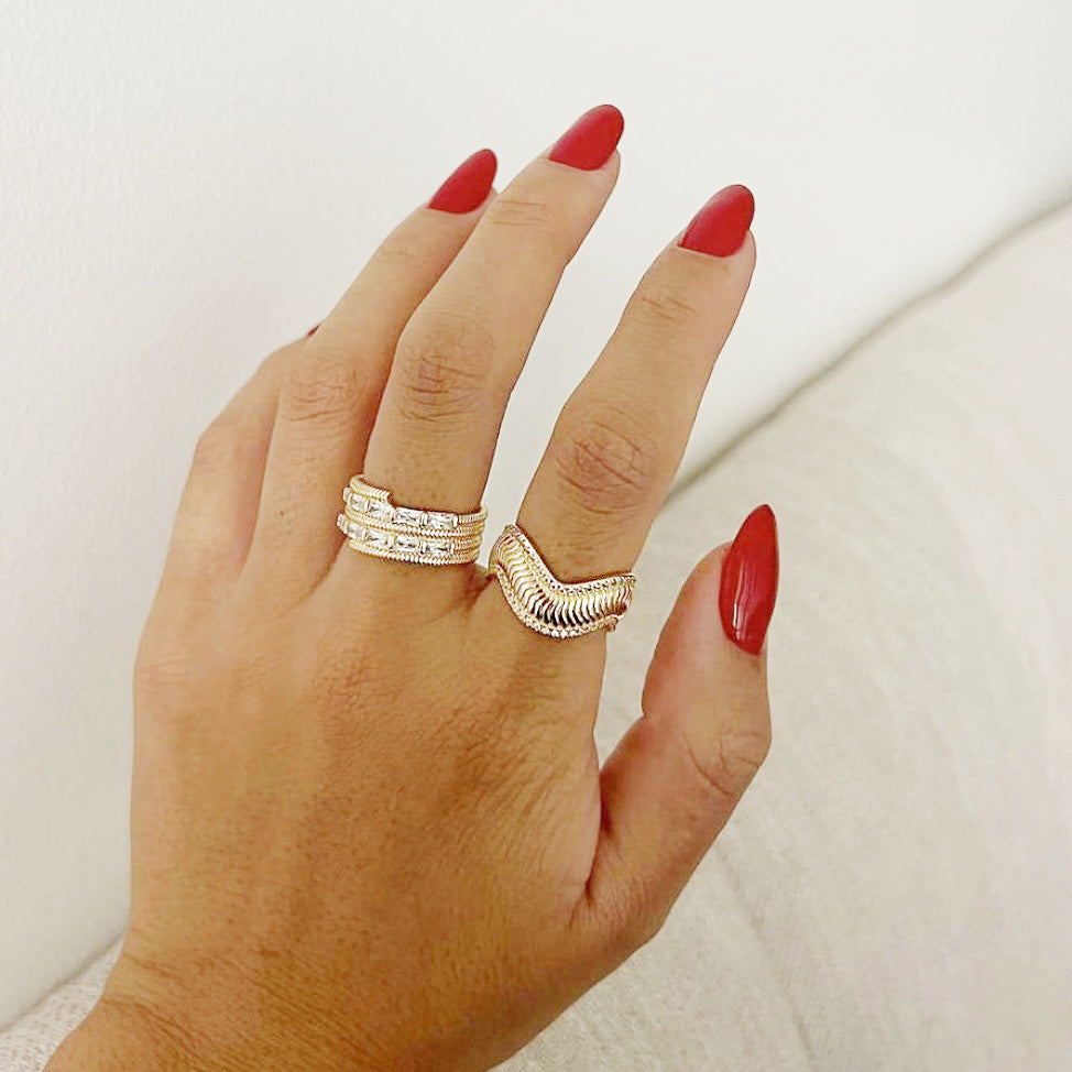 A model's hand with red nails showcasing two of the gold wavy rings from the set.