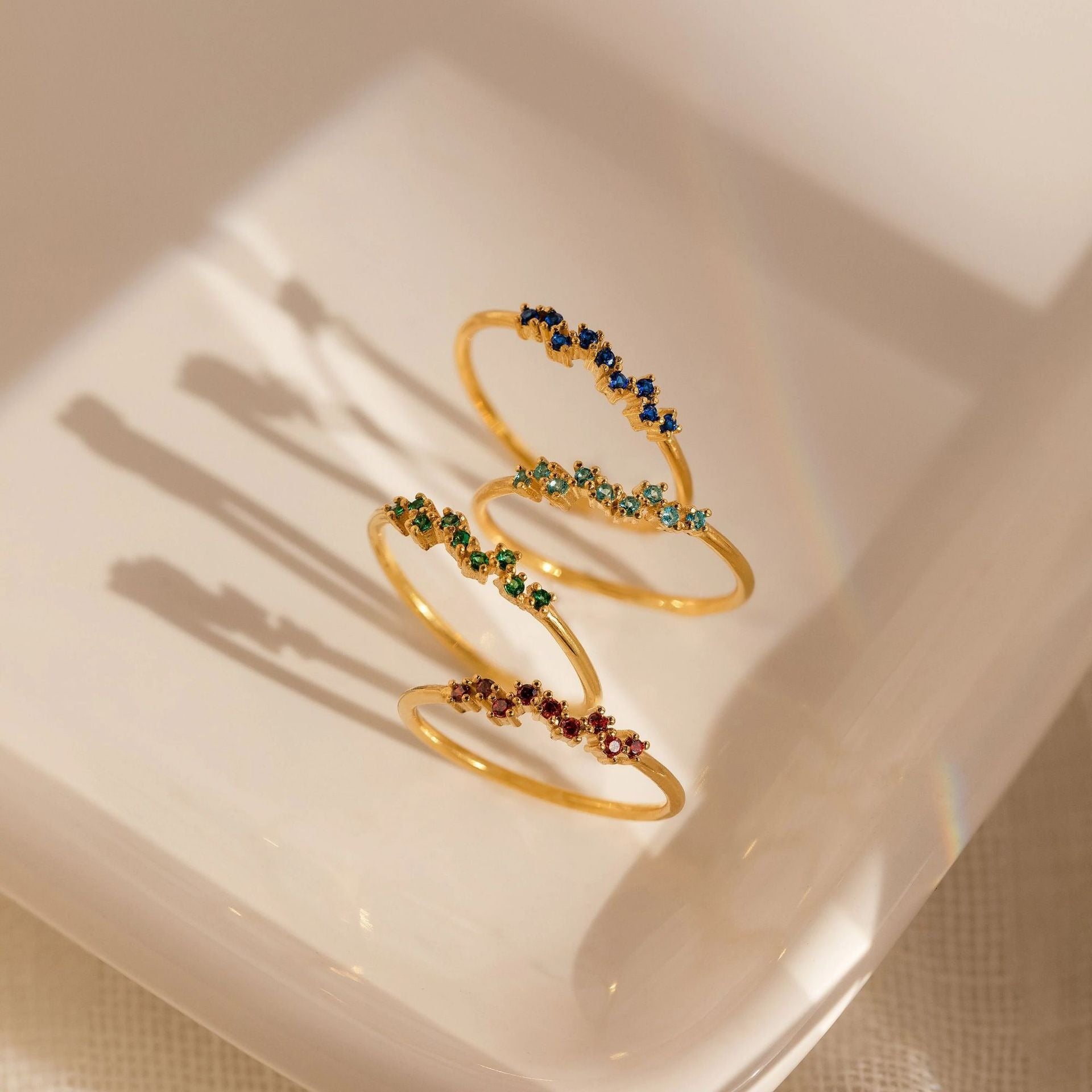 Three gold-plated sterling silver birthstone rings with different colored gems