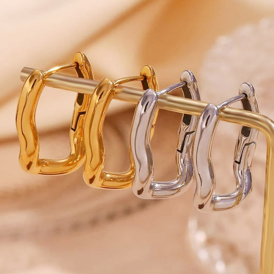 A display of various stainless steel earring styles including wavy and geometric designs