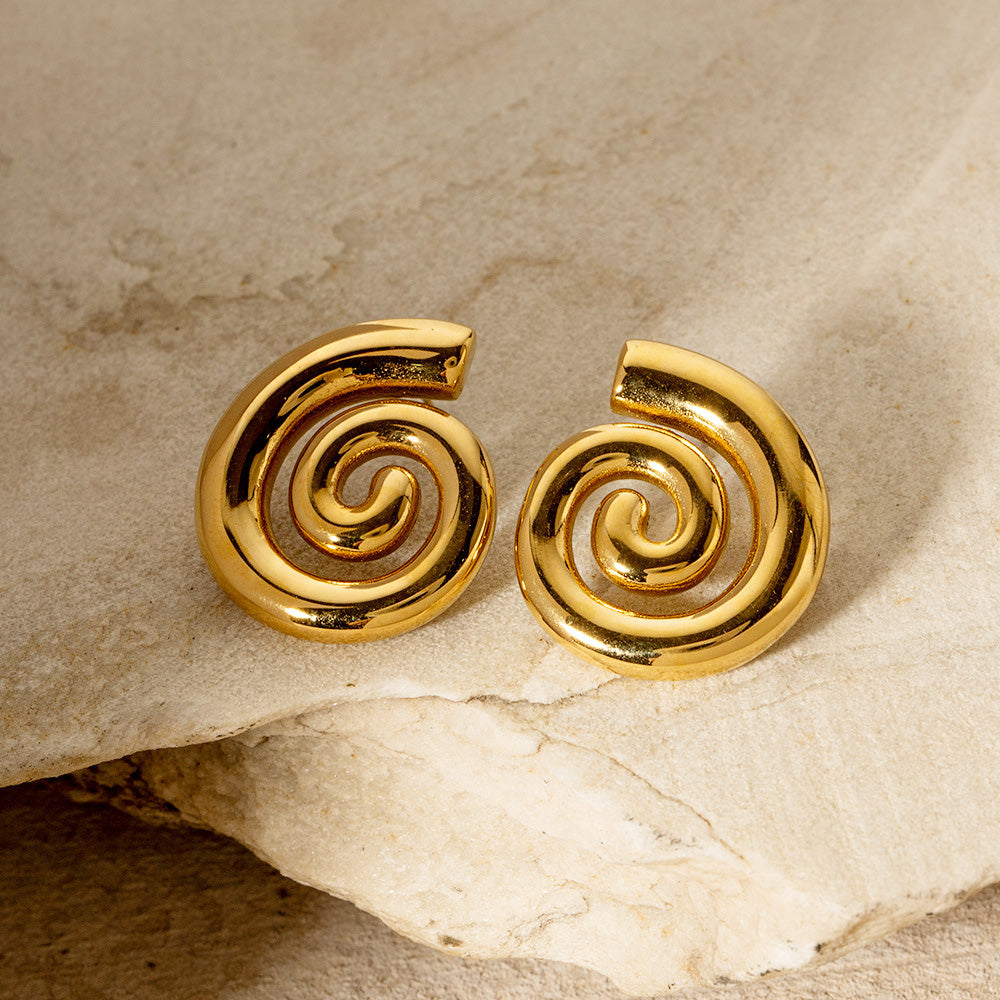 Gold spiral earrings displayed on a natural stone for a chic look