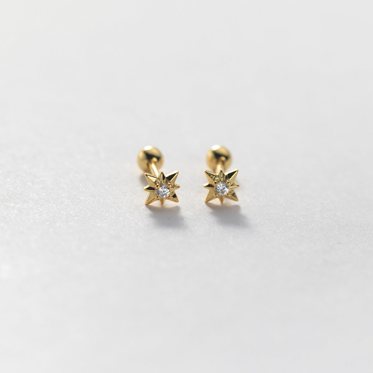 Detailed view of a gold star stud earring with a clear cubic zirconia