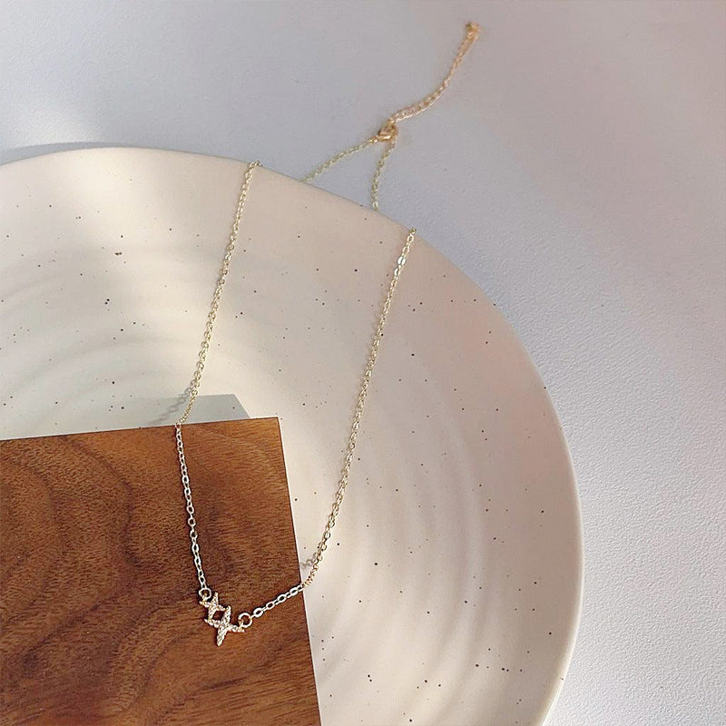 Gold-plated double-star necklace displayed on a decorative plate to showcase its design.