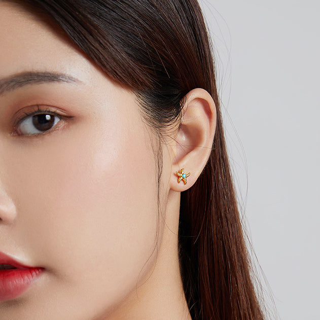 A close-up view of the gold starfish earring being worn, showing its texture and shine.