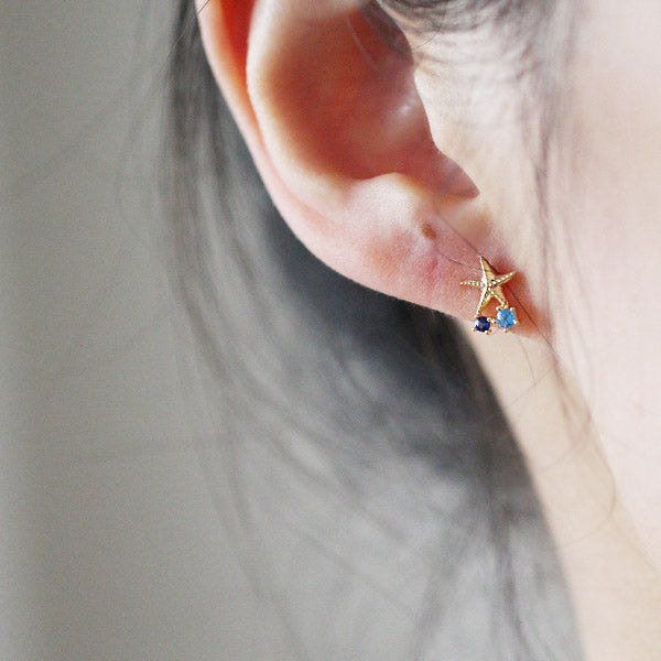 Close-up of a 925 sterling silver starfish stud earring with blue gemstone details