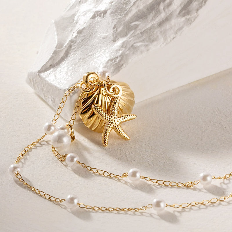 Detailed view of the gold starfish and scallop shell pendant with a pearl accent